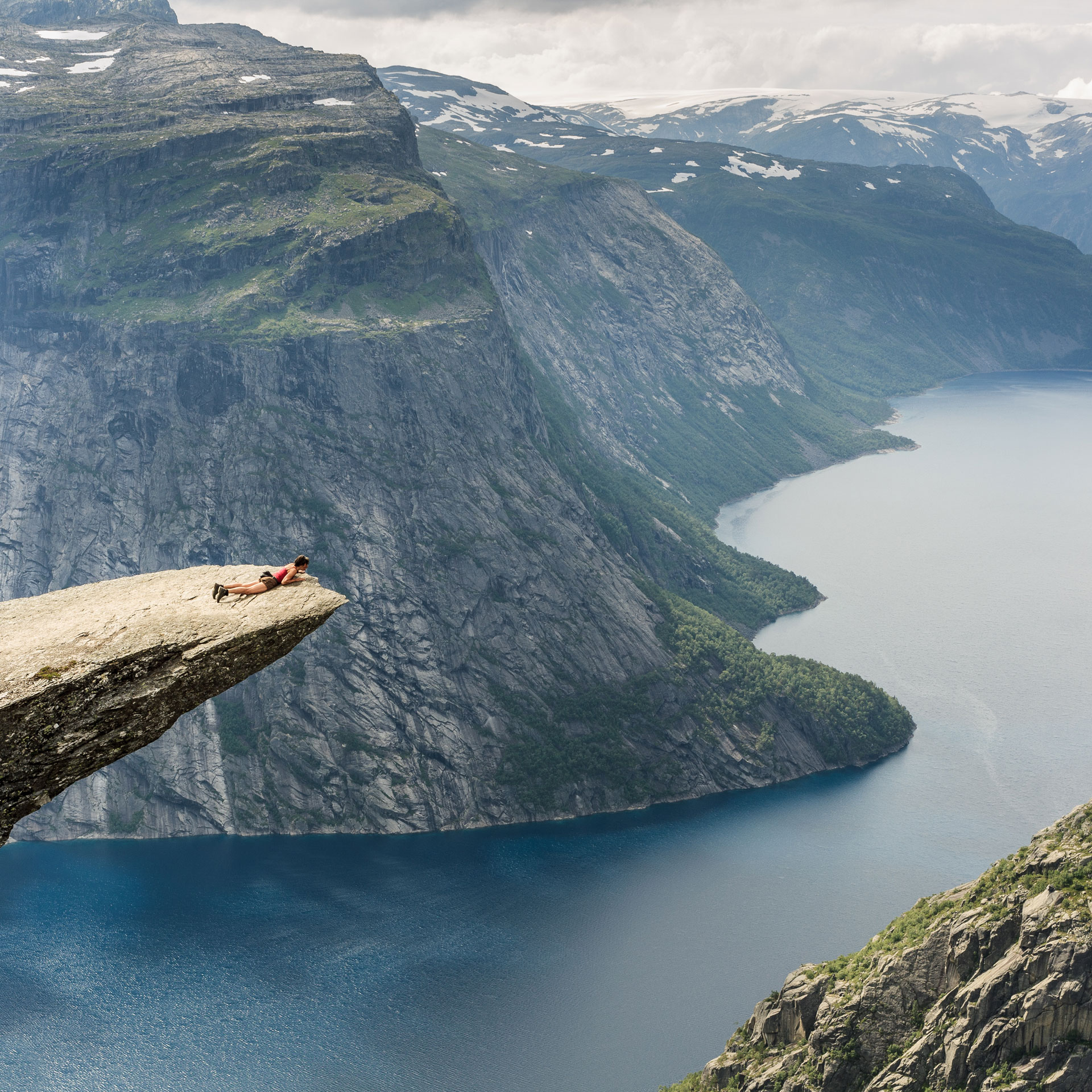 Big background image of lady lying on Trolltunga in Norway.